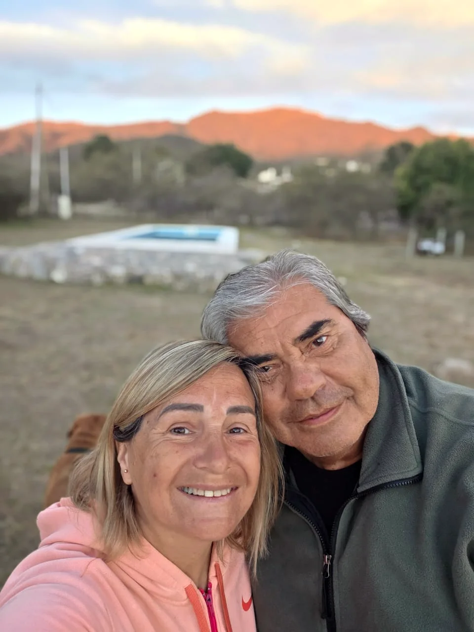 Silvi y Raúl, anfitriones de Refugio La Yaya, sonriendo, con las sierras al atardecer de fondo