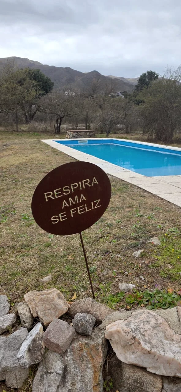 Cartel de hierro con la frase Respira, ama, sé feliz junto a la pileta